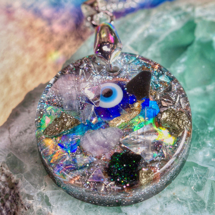 Close-up of a round pendant with crystals and an eye on a stone surface
