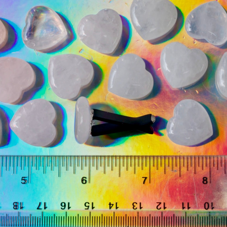 Heart-shaped stones on a colorful background with a ruler for scale.
