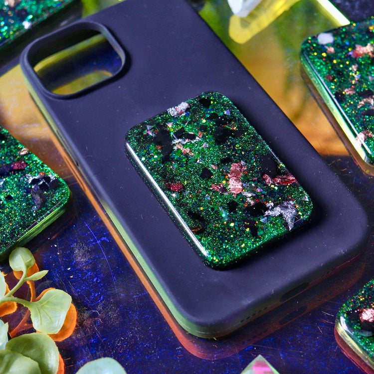Phone case with green glittery design on a reflective surface