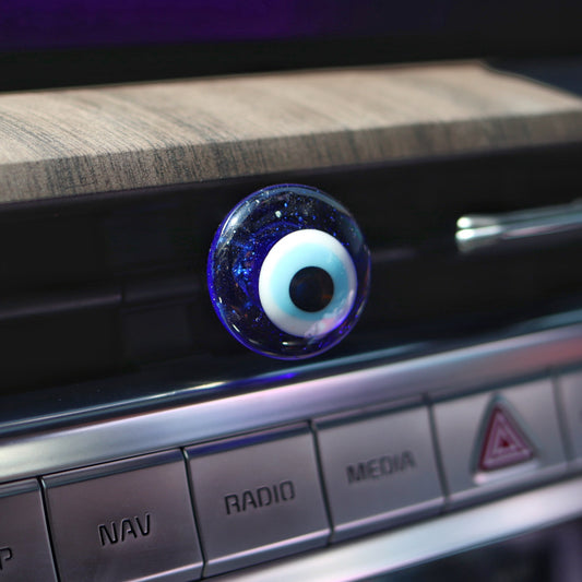 Car dashboard with a decorative evil eye charm on a wooden surface