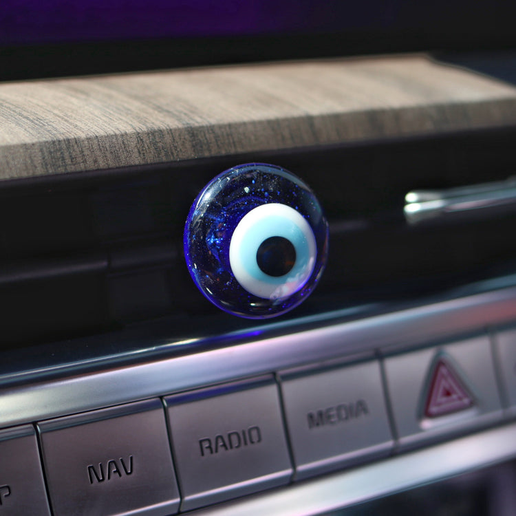 Car dashboard with a decorative evil eye charm on a wooden surface