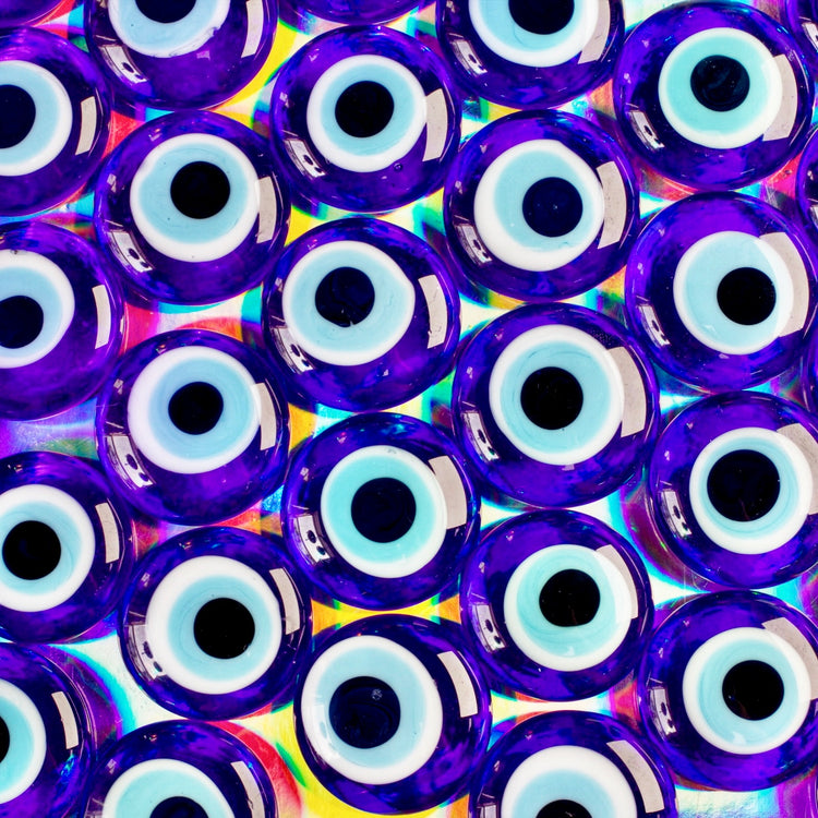 Pattern of blue glass beads with black and white centers on a colorful background