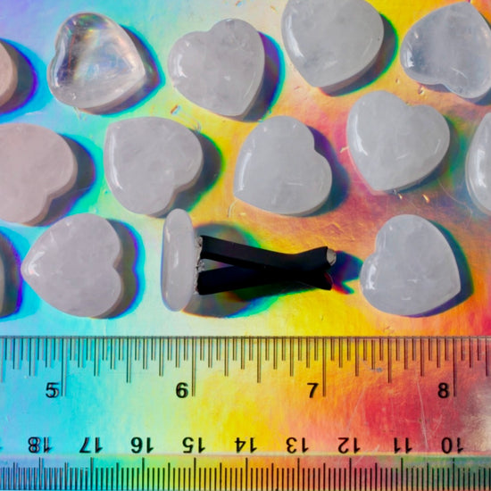 Heart-shaped stones on a colorful background with a ruler for scale.