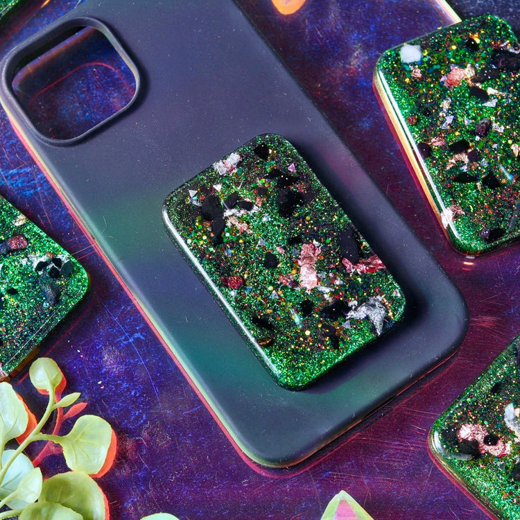 Green glittery phone case on a dark surface with plants